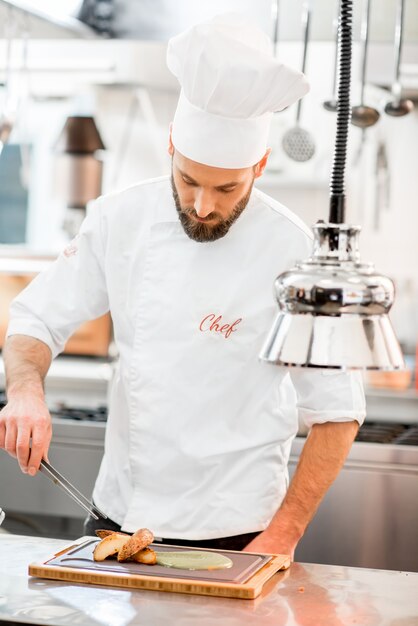 Chef cook in uniform finishing delicious meal at the restaurant kitchen