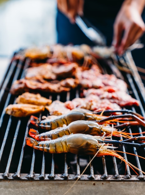 Chef cooking BBQ with shrimp grilled, pork and chicken's wing while summer holidays