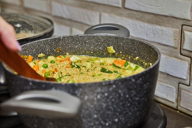 Фото Шеф-повар готовит вкусный суп из кускуса со свежей зеленью на газовой плите