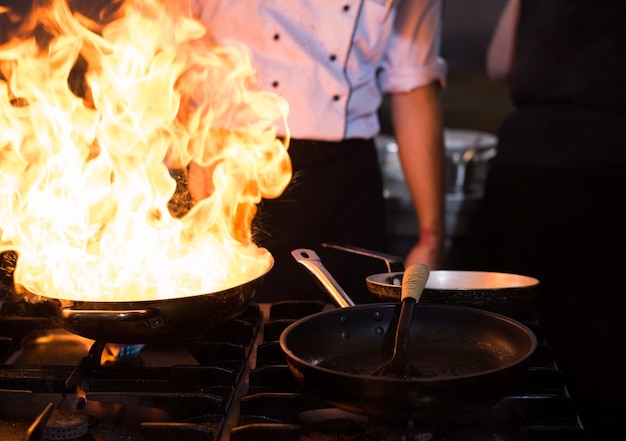 Chef cooking and doing flambe on food in restaurant kitchen