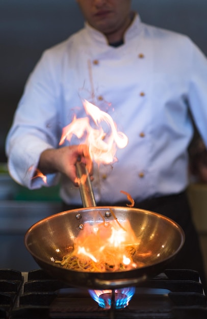 Chef cooking and doing flambe on food in restaurant kitchen