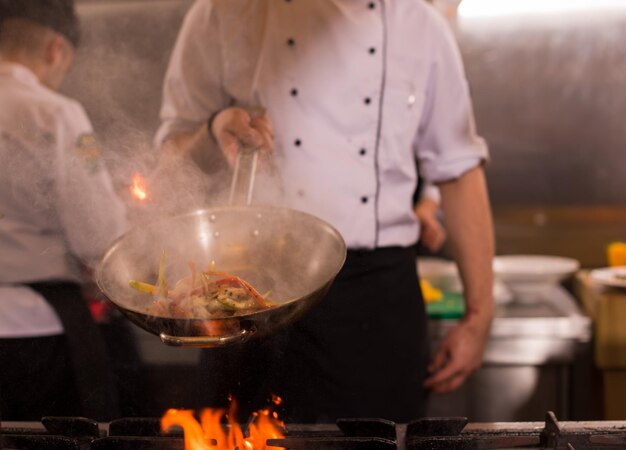 Chef cooking and doing flambe on food in restaurant kitchen