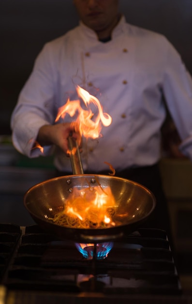 シェフがレストランの厨房で料理をし、フランベを作る