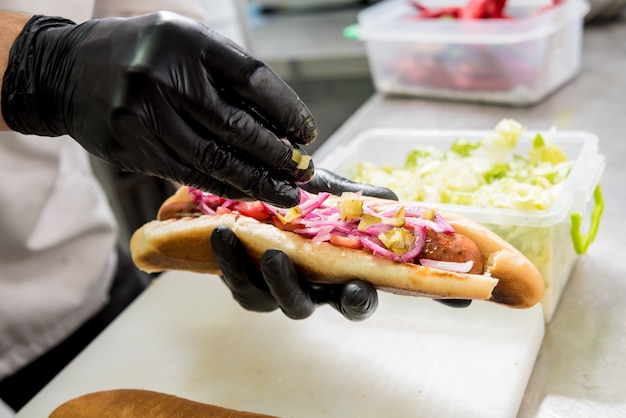 Foto lo chef cucina hot dog su una griglia. ristorante.