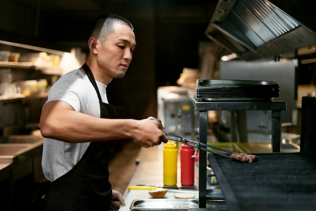 写真 専門服を着てキッチンで料理をしているシェフ