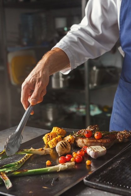 Chef cooking juicy beef steak at restaurant kitchen