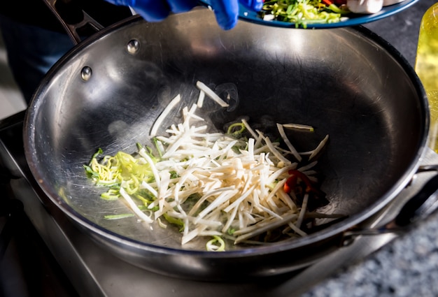 Chef cooking pasta with vegetables in pan. Italian style cuisine. Restaurant.