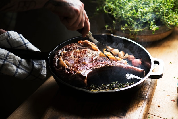 Foto cuoco unico che cucina una bistecca in un'idea di ricetta di fotografia dell'alimento della pentola