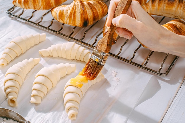 The chef cooks croissants in the kitchen in the morning on the table readymade and raw croissants and the same ingredients for their preparation