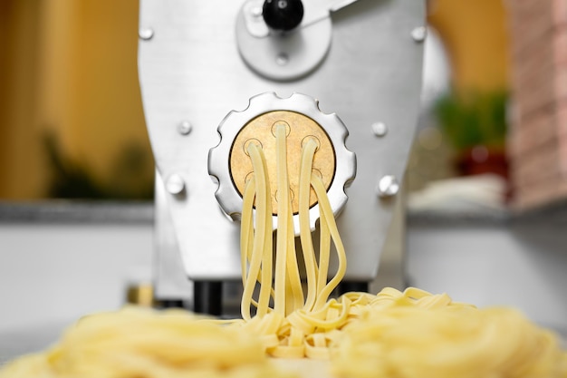 Chef cooks Italian spaghetti using a pasta machine Pulling out long pasta in restaurant kitchen