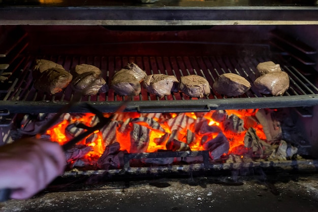 シェフがレストランの石炭で肉を調理します