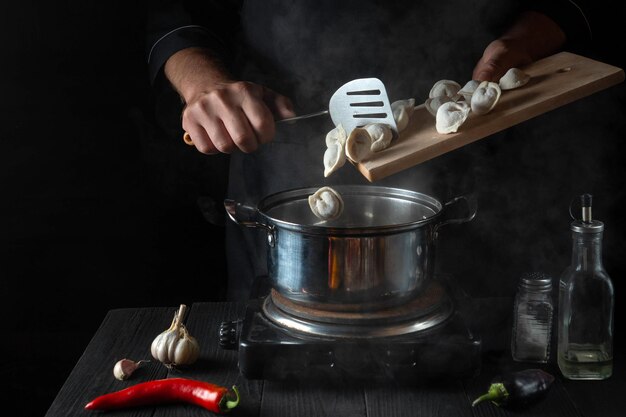 The chef cooks meat dumplings in a saucepan in the restaurant kitchen