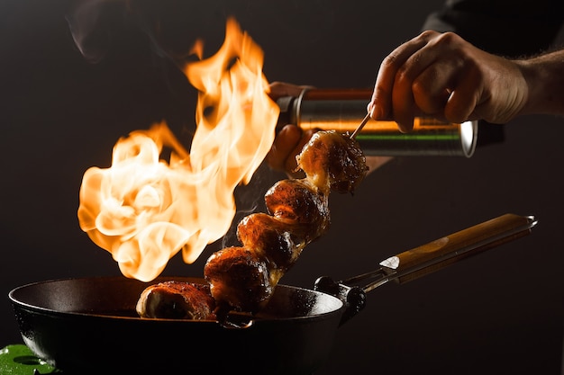 Chef cooks mushrooms in a frying pan with open fire