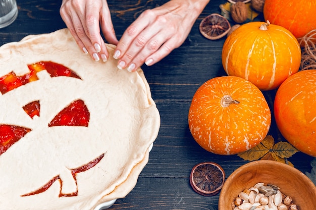 Chef cooks a pie for Halloween with a filling of pumpkin-strawberry jam and peaches