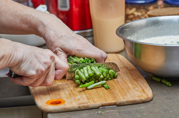 Lo chef taglia gli asparagi con il coltello per realizzare prodotti da forno con asparagi e piselli. ricetta passo passo.