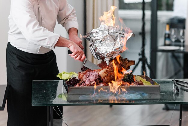 Photo chef cuts baked turkey on a platter in the fire roast turkey