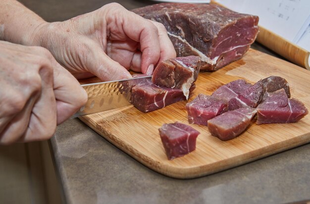 Chef cuts the beef meat into cubes for cooking