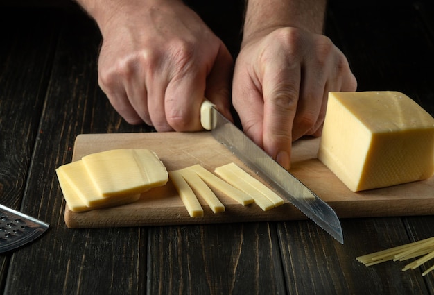 The chef cuts cheese on a cutting board before preparing pizza