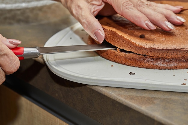 Lo chef taglia in due la torta al cioccolato per fare la torta di pere e noci