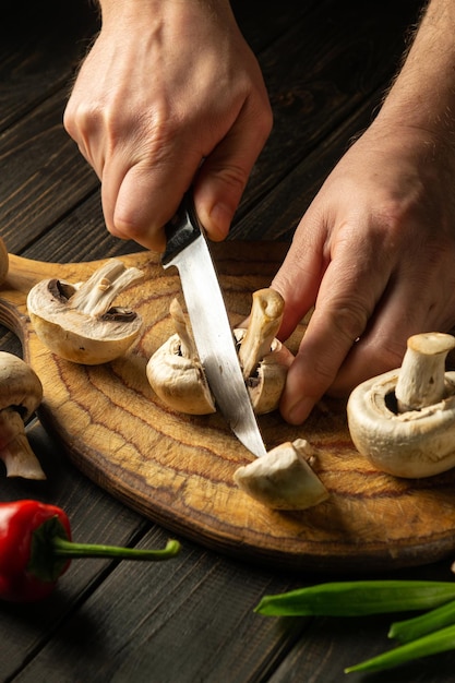 The chef cuts mushrooms Agaricus with knife to prepare delicious food