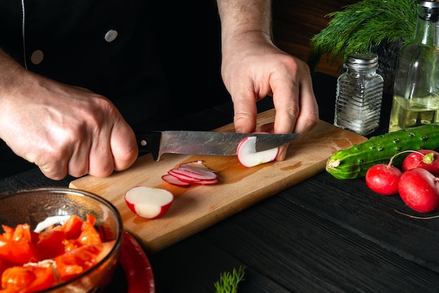 Chef cuts radishes in a vegetable salad