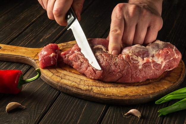 The chef cuts raw beef meat on a cutting board before baking European cuisine Hotel menu recipe idea