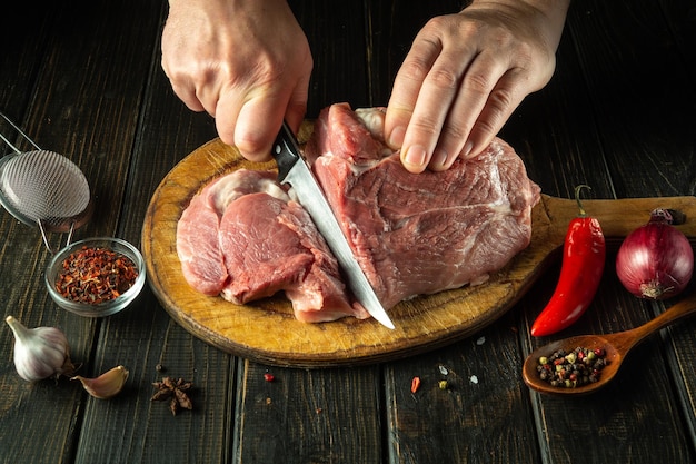 The chef cuts raw meat with a knife before grilling Preparing beef meat before roasting