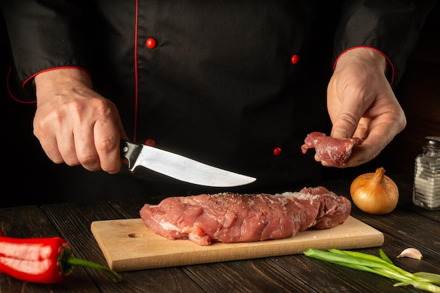 The chef cuts raw veal on a cutting board with a knife before cooking Asian food Hotel Recipe Idea