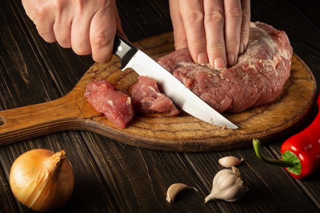 The chef cuts raw veal on a cutting board with a knife before cooking Asian food Hotel Recipe Idea