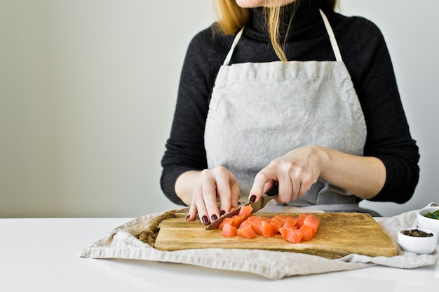 Chef cuts salmon fillet on a wooden chopping Board. 