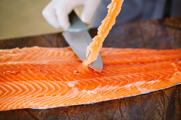 The chef cuts the salmon on the table.