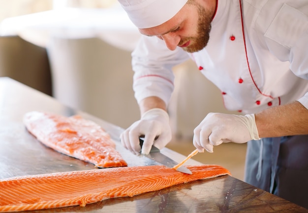 The chef cuts the salmon on the table