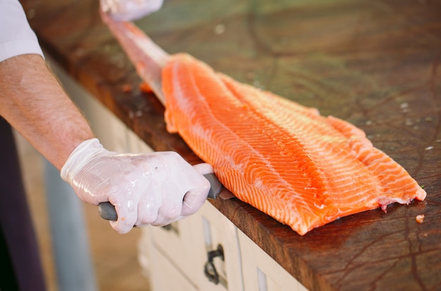 Шеф-повар режет лосося на столе