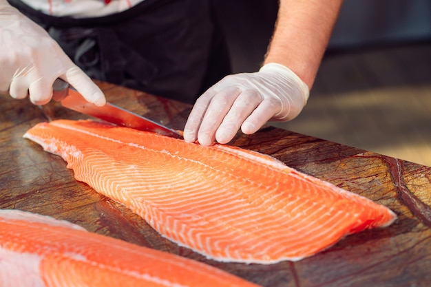 The chef cuts the salmon on the table.