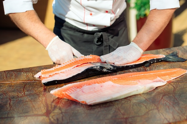 The chef cuts the salmon on the table.