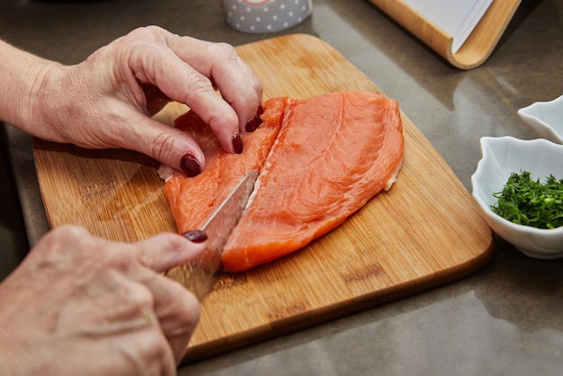 Chef cuts salmon with knife to prepare recipe