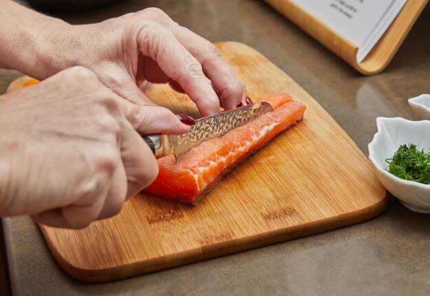 Chef cuts salmon with knife to prepare recipe