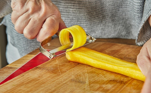 Chef cuts slices of Carrots of three colors in the kitchen on wooden board