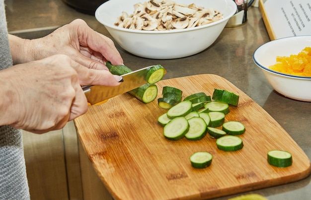Chef cuts zucchini for salad on wooden board in the kitchen