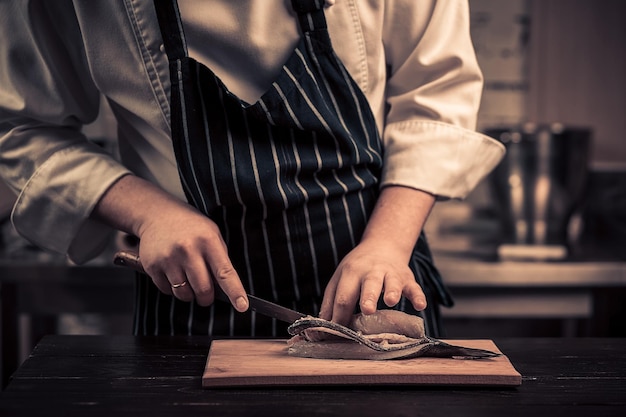 Chef cutting the fish on a board