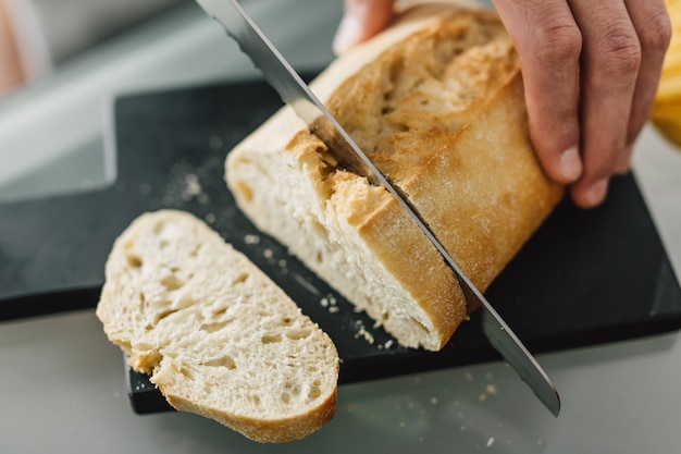 Cuoco unico che taglia pane italiano fresco