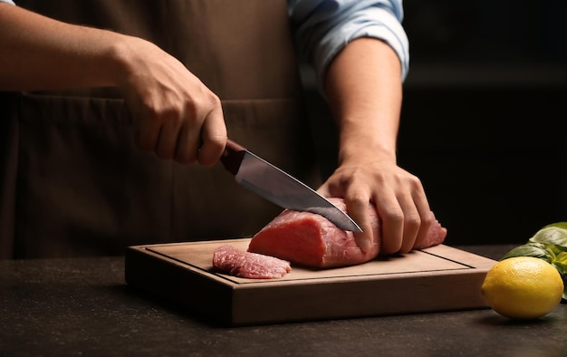 Фото Шеф-повар резки свежего сырого мяса на деревянной доске
