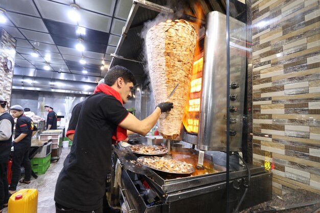 Chef cutting meat from shawarma spit spinning grillers premium photos