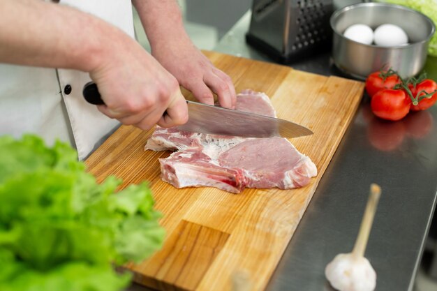 Chef cutting the meat on a wooden board