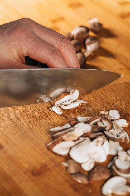 Chef Cutting Shiitake Mushrooms with Knife on a Wooden Cutting Board