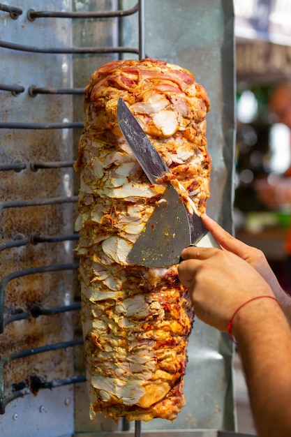 Chef cutting with doner knife traditional turkish doner kebab\
meat