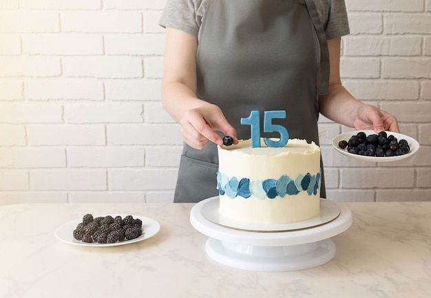 シェフがブルーベリーとブラックベリーでケーキを飾ります。 15歳の誕生日のケーキ