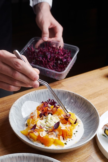 The chef decorates microgreens salad leaves to pumpkin and stracciatella salad