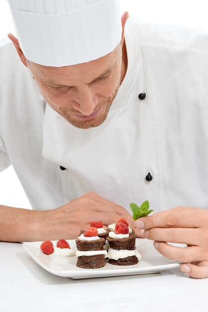 Chef dessert and mint on sweet food by culinary cook with chocolate recipe on a plate isolated in white studio background Cooking presentation and man making mini cakes as cuisine for fine dining