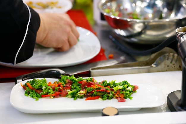 Chef finishing her plate and almost ready to serve at the table Only hands Finally dish dressing steak meat with green salad